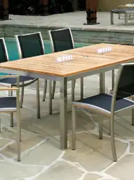 Outdoor poolside dining table with eight metal-and-wood chairs on a stone patio.