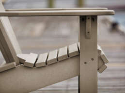 Beige wooden outdoor lounge chair with an adjustable backrest on a wooden deck.